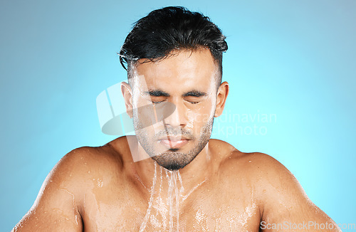 Image of Water, face and facial by man for beauty, skin and skincare and topless wash or shower. Mexican, male and wellness model with moisture, cleanse and hydration isolated in studio blue background