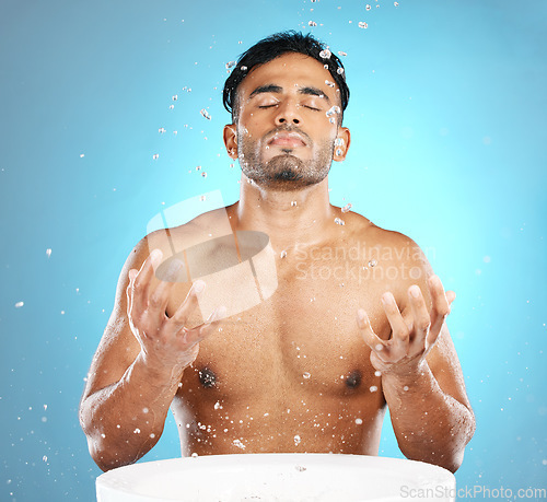 Image of Facial, skincare and man in studio for water splash, wellness and grooming on blue background. Cleaning, beauty and moisture by Mexican model relax with luxury, routine and facial wash while isolated