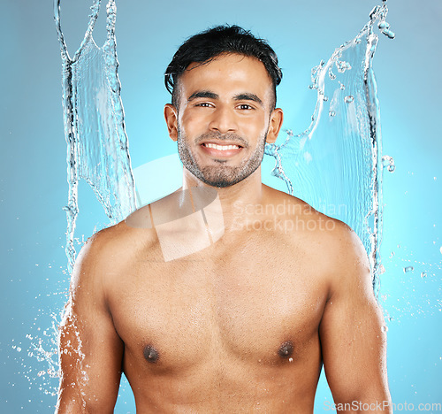 Image of Water, splash and portrait of man for beauty, skin and skincare cleaning his body, muscle and topless. Mexican, male model with moisture, cleanse and hydration isolated in studio blue background