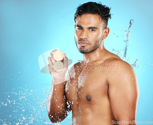 Image of Lemon, skincare and portrait of man in water splash in studio for wellness, cleaning and fresh on blue background. Fruit, product and beauty by male model relax with luxury, facial and skin treatment