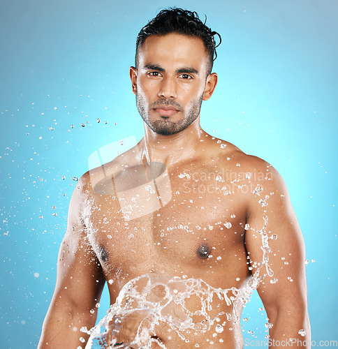 Image of Portrait, splash and beauty, skin and skincare man cleaning his body, muscle and topless. Water, male and wellness model with moisture, cosmetic and hydration isolated in studio blue background