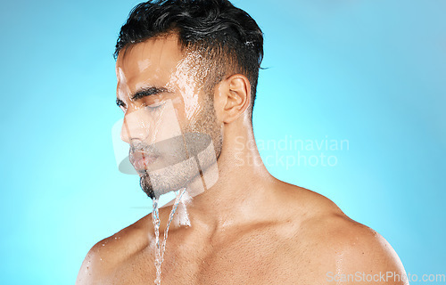 Image of Shower, skincare and man in studio for water splash, hygiene and grooming on blue background. Cleaning, skin and Mexican model relax with luxury, moisture and wash routine while standing isolated