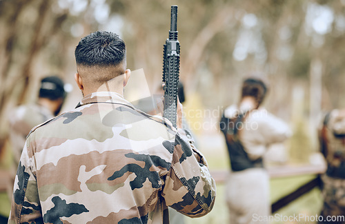 Image of Paintball, soldier or man with a gun in a shooting game playing on a fun battlefield in nature or forest. Back view, military or warrior with weapons gear for survival in an outdoor competition