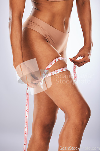 Image of Leg, measuring tape and woman in studio for weightloss, diet and health progress on gray background. Isolated legs of female model with body for size check, measure and slimming results in underwear