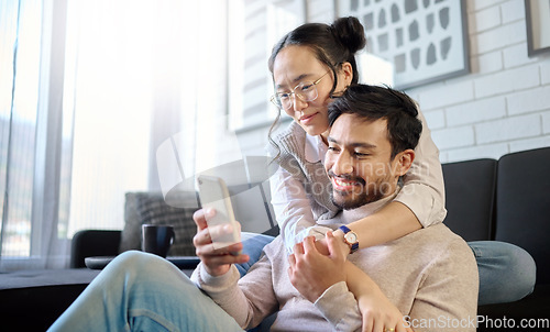 Image of Phone, love and diversity with a couple in their home, bonding while browsing social media in the living room. Mobile, communication or internet with an interracial man and woman together in a house