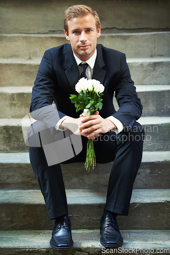 Image of Stairs, portrait and man with flowers for valentines day, romance or gesture while sitting outdoors. Roses, face and gentleman with bouquet for love, anniversary or first date, confident and handsome