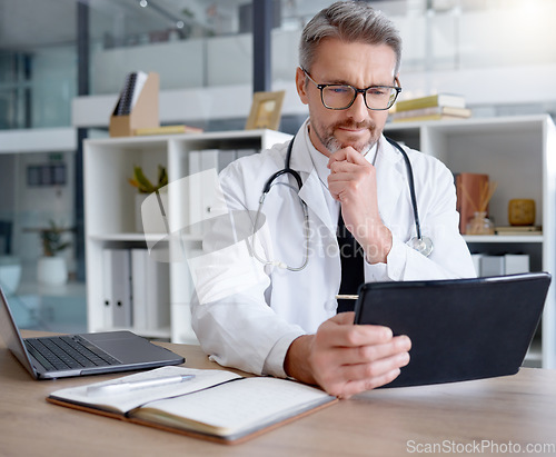 Image of Thinking doctor, tablet and man in hospital for telehealth, online consultation or healthcare. Medical technology, wellness ideas or mature male physician with digital touchscreen for health research