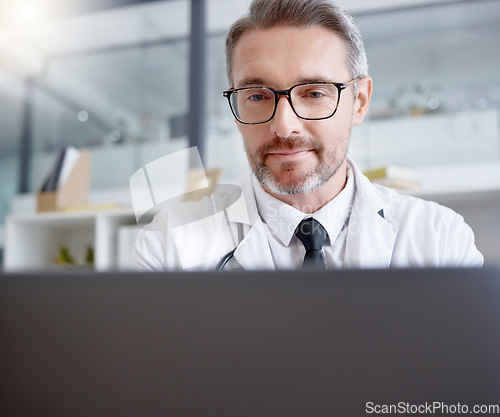 Image of Laptop, man and doctor working in hospital for healthcare, health and wellness in clinic. Computer research, medical professional or mature physician writing report, telehealth or online consultation