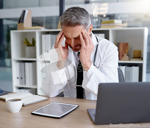 Image of Doctor, burnout and man with headache in hospital feeling depressed while working on laptop. Mental health, depression and medical professional or physician with stress, pain and anxiety in clinic.