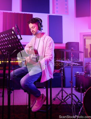 Image of Musician, headphones or guitar in neon studio, recording production or performance on radio mic, label or band concert. Guitarist, artist or man playing on strings instrument in night light practice