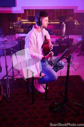 Image of Artist, headphones or guitar in neon studio, recording production or performance on radio mic, label or band concert. Guitarist, musician or man playing on strings instrument in night light practice