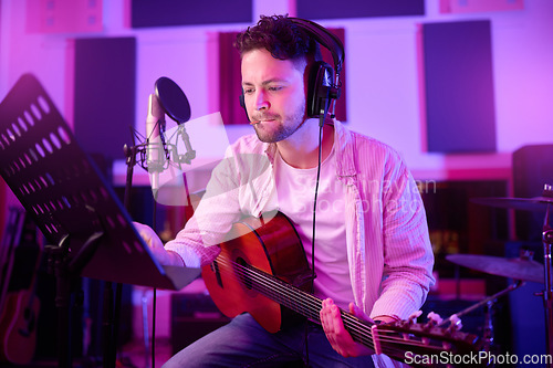 Image of Man, headphones or guitar in neon studio, recording production or performance on radio mic, label or band concert. Guitarist, artist or thinking musician on strings instrument in night light practice