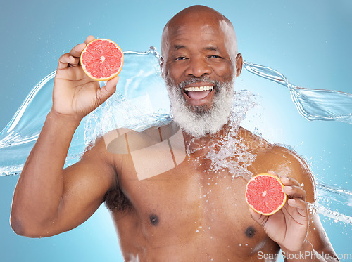 Image of Black man, portrait smile and grapefruit for skincare nutrition, vitamin C or hydration against a blue studio background. Happy African American male smiling and holding fruit for health and wellness