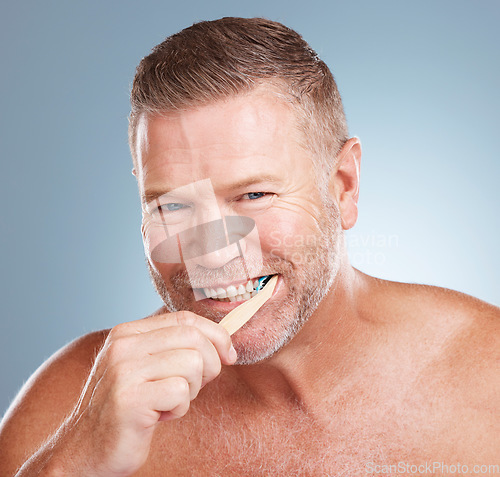 Image of Happy, mouth or old man brushing teeth with dental toothpaste products for healthy oral hygiene in studio. Eco friendly, portrait or senior person cleaning gums with a natural bamboo wood toothbrush