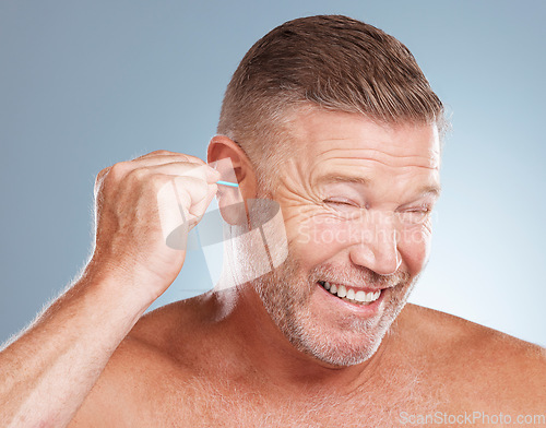 Image of Man, ear bud and grooming in skincare, cosmetics or hygiene products against a gray studio background. Male person cleaning ears for body care or self love in clean beauty, health and wellness