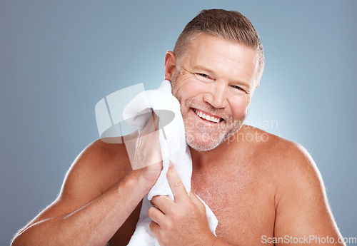 Image of Skincare, portrait and happy old man in studio with towel for facial, cleaning or grooming on grey background. Face, mature and male model relax with luxury, skin or beauty treatment while isolated