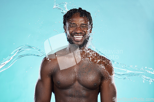 Image of Water splash, studio and black man isolated on blue background with face cleaning, body and skincare beauty. Strong, muscle and happy model or person in shower aesthetic, wash and dermatology hygiene