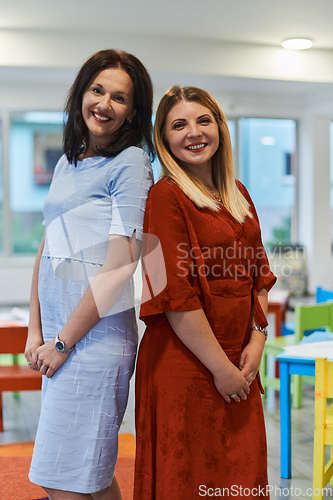 Image of Portrait of a two teacher in a preschool institution, in the background of the classrooms