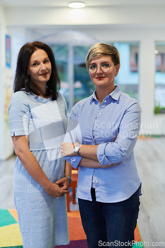 Image of Portrait of a two teacher in a preschool institution, in the background of the classrooms