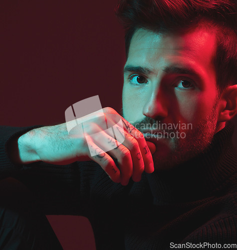 Image of Man, fashion and studio portrait with red light for clothes, hand tattoo and luxury style on dark background. Face of aesthetic model person with turtle neck, art and cosmetic for inspiration for men