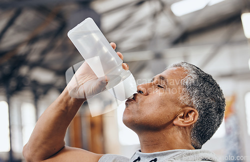 Image of Man, fitness and drinking water bottle for hydration after workout, exercise or cardio training indoors. Sporty male staying hydrated for healthy endurance, recovery or thirst from sports exercising