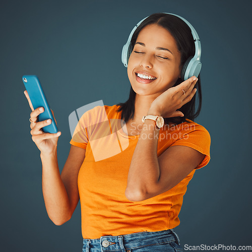 Image of Radio, headphones and woman listening to music on phone or mobile app isolated against a studio background. Fun, sound and female enjoying and streaming a podcast or audio smiling and happy