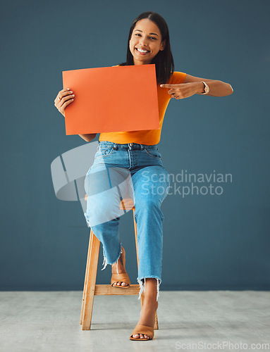 Image of Woman, poster portrait and pointing at mockup banner space for sale, discount or promotion. Happy model with advertising for product placement, logo or branding on billboard or orange paper in studio