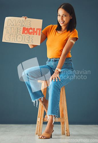 Image of Woman, vaccine poster and studio portrait with smile, stop covid and healthcare opinion on cardboard. Happy gen z girl, billboard or wellness decision with plaster, sign and happy for safety in home