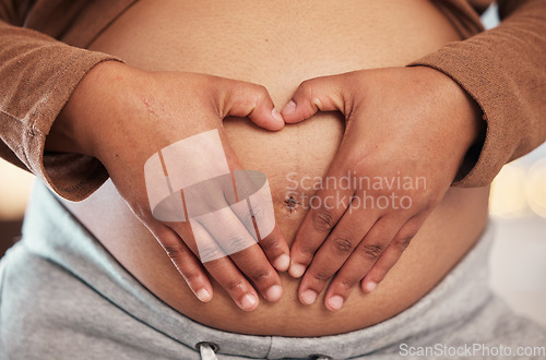 Image of Pregnant woman, closeup of heart hands on belly and happy black mother alone in Jamaica living room. Excited future parent, holding healthy abdomen at home and loving mommy in pregnancy care
