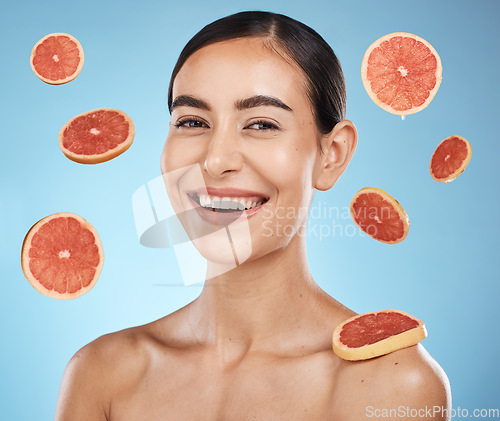 Image of Woman, studio portrait and grapefruit with beauty skincare, smile or happy for wellness by blue background. Young gen z model, healthy face skin or citrus fruit for vitamin c with self care happiness