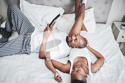 Image of Black couple, tablet and relaxing on bed with smile for entertainment, browsing or social media at home. Happy African American man and woman chilling in bedroom on touchscreen for morning streaming