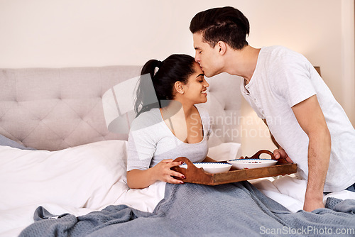 Image of Breakfast in bed, food and couple at home together with a kiss, care and love in a house. Valentines day, relax and smile of an Indian woman and man in the morning in bedroom with tray and happiness