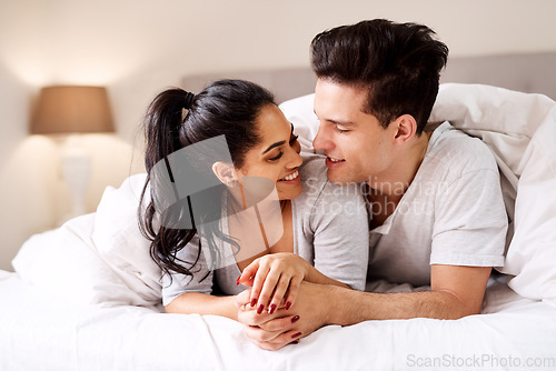 Image of Bedroom, love and interracial couple together in home holding hands at night. Smile diversity and marriage of an Indian woman and man with love, care and relax happiness with a smile in a house