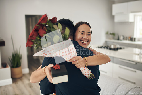 Image of Couple hug, home and roses present surprise of an Asian woman on valentines day. Living room, rose bouquet and lounge of people with love, care and happiness together with a smile from present