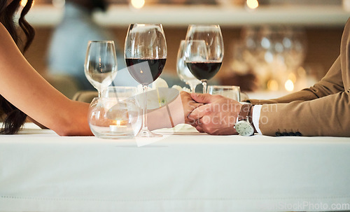 Image of Love, wine and couple holding hands in restaurant for romantic dinner, date and anniversary celebration. Relationship, fine dining and man and woman together for luxury date, alcohol and honeymoon