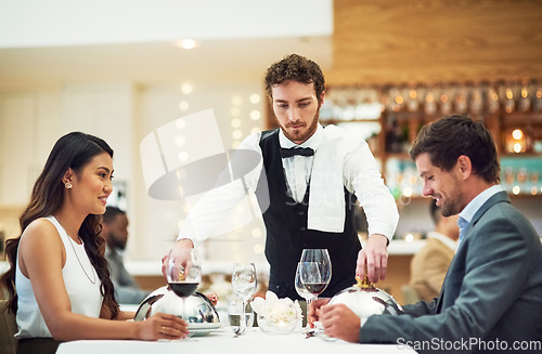 Image of Couple, restaurant server and fine dining at table for valentines day date, bonding and romance in night. Man, woman and waiter with food, service and hospitality for dinner, love and celebration