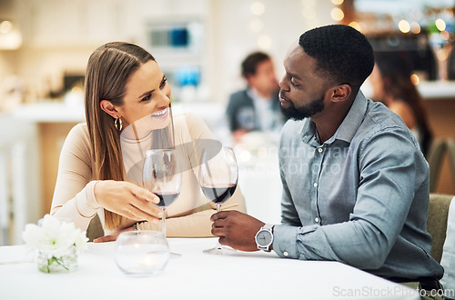 Image of Love, wine and interracial couple on date for fine dining, restaurant or valentines celebration together. Black man and happy woman with romance alcohol glasses, celebrate and luxury in night bokeh