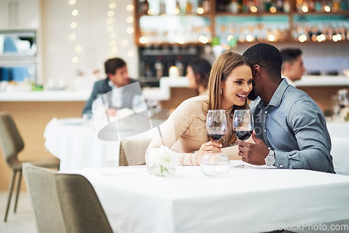 Image of Restaurant date, couple and wine celebration of a man telling a secret at a dinner table. Anniversary celebration, valentines day smile and wine at night with love, care and conversation together