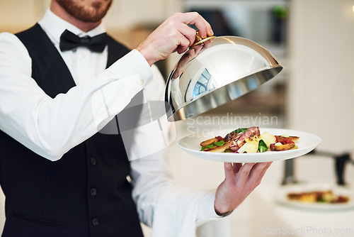 Image of Waiter, hands and opening plate of food for serving, meal or customer service at indoor restaurant. Man employee caterer or server catering or bringing open dish for fine dining, hospitality or order