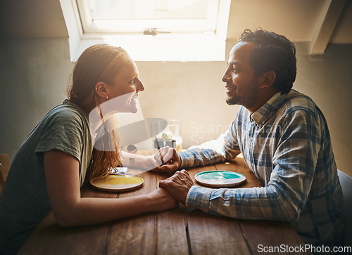 Image of Love, couple and holding hands at home on table, talking and bonding together. Valentines day, romance diversity and affection of man and woman on date, having fun and enjoying quality time in house.