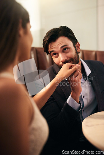 Image of Hand, kiss and love with a couple in a restaurant on a date night out together for fine dining or luxury. Love, romance and affection with a man kissing his wife while dating in celebration