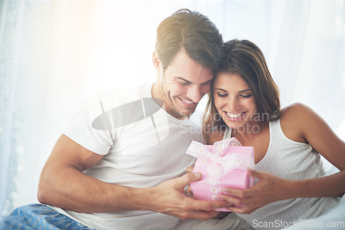 Image of Love, gift and valentines day with a couple in a bedroom of their home together for a romantic celebration. Birthday, box or present with a young man and woman bonding in bed to celebrate in a house