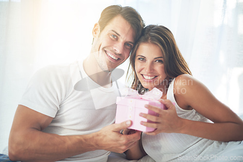 Image of Portrait, gift and valentines day with a couple in bed together at home for a romantic celebration. Love, box or present with a man and woman in the bedroom of a house for a birthday or anniversary