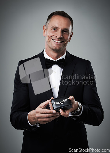 Image of Jewelry, man and portrait of a model with a smile and valentines present in a studio. Isolated, gray background and person in a suit with happiness holding a necklace gift feeling love and classy