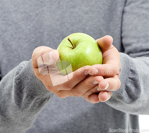 Image of Hand, health and man in a studio with a apple for nutrition, diet and a healthy snack with vitamins. Wellness, natural and healthy male person with fresh, organic and raw green fruit for a craving.