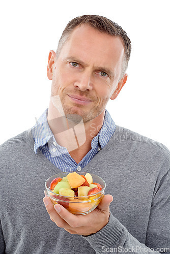 Image of Portrait, fruit salad and unhappy with a mature man in studio isolated on a white background for health eating. Face, food and upset with an annoyed male on blank space feeling negative about a diet