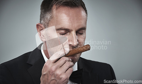 Image of Suit, luxury and man smell cigars for smoking habit on gray background for mafia, power and success mockup. Mafia, business gangster and face of senior male with cigarette for smoke, relax and calm