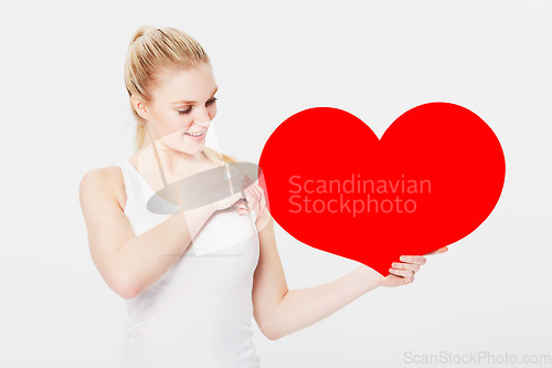 Image of Valentines day, happy and woman with a heart in a studio with a smile for a romantic gesture. Happiness, excited and female model from Australia holding a love shape isolated by a white background.