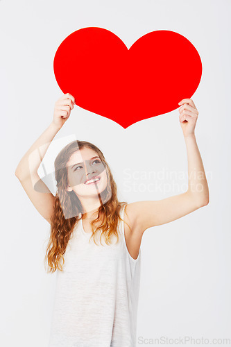 Image of Love, showing and girl with a cardboard heart isolated on a white background in a studio. Smile, care and happy woman holding a paper shape for romance, attraction and valentines day on a backdrop