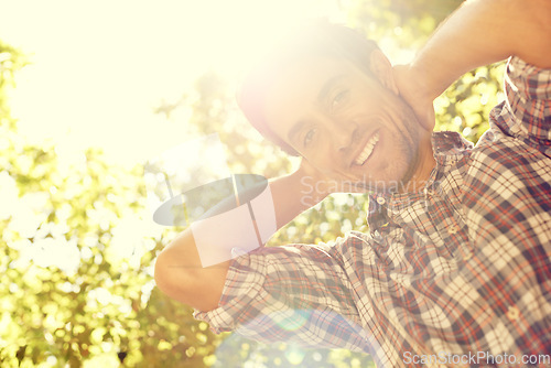 Image of Sun, man and portrait in an outdoor park with lens flare from sunshine in summer. Happy, smile and nature with a young person by trees feeling relax, calm and positive on a sunny day in a garden